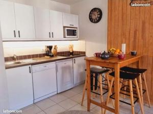 a kitchen with white cabinets and a wooden table at Appartement T2-5 couchages L'écrin des Orres 1800 in Les Orres