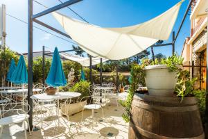 a patio with tables and chairs and a white umbrella at Hôtel Restaurant - Villa Les Sirènes in Argelès-sur-Mer