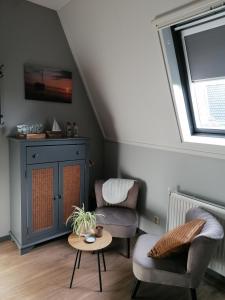 een woonkamer met 2 stoelen en een tafel bij Tusken Wad en Wâld in Kollumerzwaag