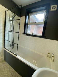 ein Bad mit einer Badewanne, einem Waschbecken und einem Fenster in der Unterkunft 1 bed flat with parking near town centre in Emsworth