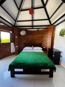 a bedroom with a green bed in a brick wall at Finca Vacacional Guanani in Socorro