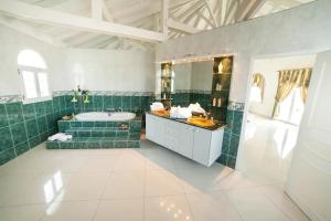 bagno con piastrelle verdi, vasca e lavandino di Villa Millésime a Le François