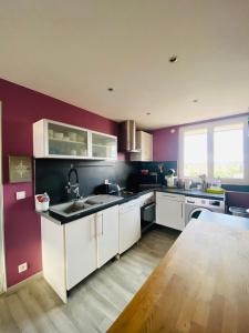 a kitchen with white cabinets and a purple wall at Appartement - Roanne in Roanne