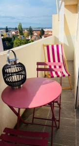 d'une table rouge et d'une chaise sur un balcon. dans l'établissement Appartement - Roanne, à Roanne