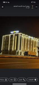 un gran edificio con luces encendidas por la noche en جوهرة السراة للأجنحة الفندقية, en Khamis Mushayt