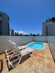 two lounge chairs and a swimming pool on a roof at A mais Charmosa acomodação em Boa Viagem. 500Mb in Recife