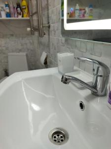 un lavabo blanco con un dispensador de jabón. en City House en Aktau