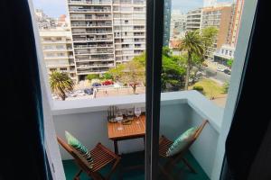 a balcony with a table and chairs and a view of a city at Rambla Apart in Montevideo