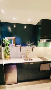 eine Küche mit einem Waschbecken und einer grünen Wand in der Unterkunft Rambla Apart in Montevideo
