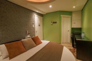 Un dormitorio con una cama con paredes verdes y un escritorio. en Motel Paradiso - Cruz Alta en Cruz Alta