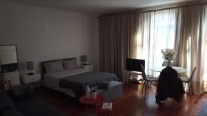 1 dormitorio con 1 cama y sala de estar con mesa en Flores Central, en Oporto