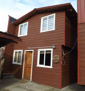 a red house with white windows and a door at Cabañas Robinson in Puerto Puyuhuapi