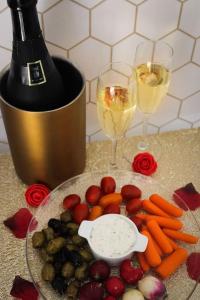 une assiette de fruits et légumes avec deux verres de vin dans l'établissement Suite romantique avec sauna et balnéo privatifs au Barcarès, au Barcarès