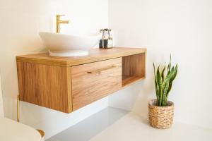 łazienka z umywalką i drewnianą toaletką z rośliną w obiekcie Rezydencja Dychów w mieście Dychów