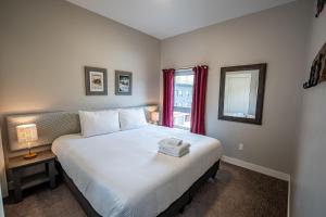 a bedroom with a large white bed with a window at Pillow Top Condo by Revelstoke Vacations in Revelstoke