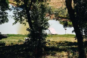 a view of a lake from behind some trees at Maison de campagne, bord de lac, piscine, billard 11 per in Plieux