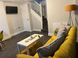 a living room with a yellow couch and a table at Maple House 2 bed House with free parking in town by ShortStays4U in King's Lynn