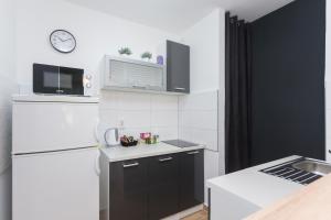 a small kitchen with a refrigerator and a microwave at Apartman Lariva in Osijek