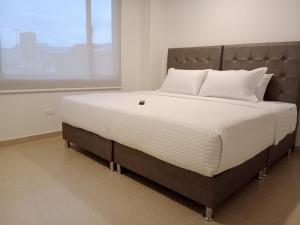 een groot bed in een kamer met een groot raam bij Aparta Suite Plaza Premium by Tourism Yossa in Bogota