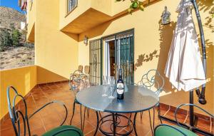 einen Tisch und Stühle mit einer Flasche Wein auf einer Terrasse in der Unterkunft 3 Bedroom Stunning Home In Cenes De La Vega in Cenes de la Vega