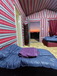 a bed in a room with a striped wall at Dana Sunset Eco Camp in Dana