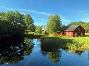 Sjöstugan, Solviken في Rockneby: حضيرة حمراء ونهر به منزل احمر