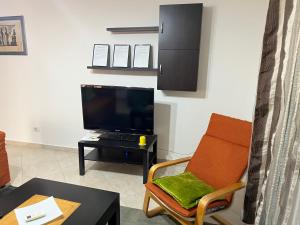 a living room with a tv and a chair and a table at Sol Apartment in Lezhë