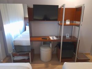 Dieses kleine Zimmer verfügt über einen Schreibtisch, ein Bett und einen Schreibtisch mit einem TV. in der Unterkunft Rochester Hotel Concept in Buenos Aires