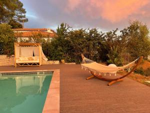 a hammock and a chair next to a swimming pool at Le domaine des Petits Princes in Lorgues
