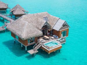 a small house with a boat in the water at InterContinental Bora Bora & Thalasso Spa, an IHG Hotel in Bora Bora