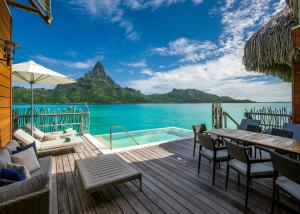 una terraza con mesa, sillas y el océano en InterContinental Bora Bora & Thalasso Spa, an IHG Hotel, en Bora Bora