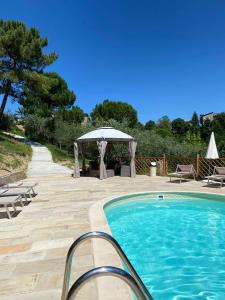 una piscina con una mesa y un cenador en Villa Mery sui colli della riviera di Rimini, en Mondaino
