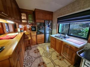 a kitchen with wooden cabinets and a large window at Habitación con baño privado A in Villarrica