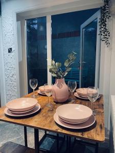 un tavolo in legno con piatti, bicchieri e un vaso di Historic Cottage in the Heart of Old Aberdeen. ad Aberdeen