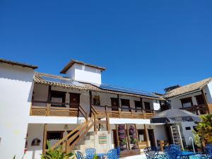 a building with blue chairs in front of it at Pousada Zimbauê in Itaúnas
