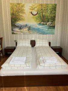 two beds in a bedroom with a painting on the wall at Къща за гости Ягода in Sapareva Banya