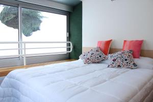 un grande letto bianco in una stanza con finestra di Natura, relax e avventura a Marilleva 1400 - HomeUnity a Marilleva