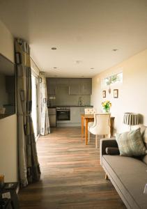 a living room with a couch and a kitchen at Sweet Pea Cabin in Badsey