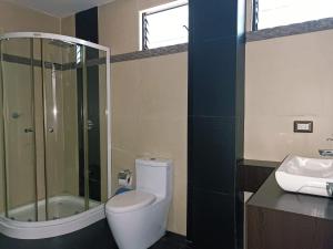 a bathroom with a shower and a toilet and a sink at Hotel Quezada Hermanos in Santo Domingo de los Colorados