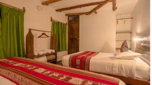 a bedroom with two beds and a mirror at MAMA GREEN Veggie Hostal & Permaculture Farm in Urubamba