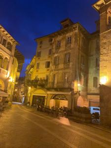 a building with tables and chairs on a street at night at Antica Dimora del Mercato in Domodossola