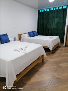 two beds in a room with blue pillows on them at Hotel Media Luna in Cúcuta