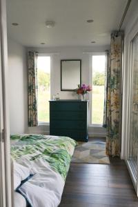 a bedroom with a bed and a dresser with a mirror at Bluebell Cabin in Badsey