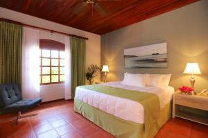 ein Schlafzimmer mit einem Bett, einem Stuhl und einem Fenster in der Unterkunft Villa del Sueño in Playa Hermosa