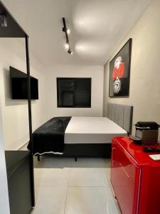 a bedroom with a bed and a red desk at Acomodações Tio Will in Guarujá
