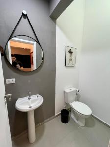 a bathroom with a toilet and a sink and a mirror at Acomodações Tio Will in Guarujá