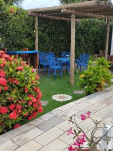 a patio with blue tables and chairs and flowers at Pousada Zimbauê in Itaúnas