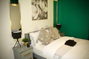 a bedroom with a white bed with a green wall at 1 Bed Apartment B in Birmingham