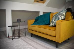 um sofá amarelo numa sala de estar com duas mesas em 1 Bed Apartment B em Birmingham