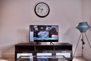 uma sala de estar com televisão e um relógio na parede em Stylish Birmingham City Centre Apartment em Birmingham